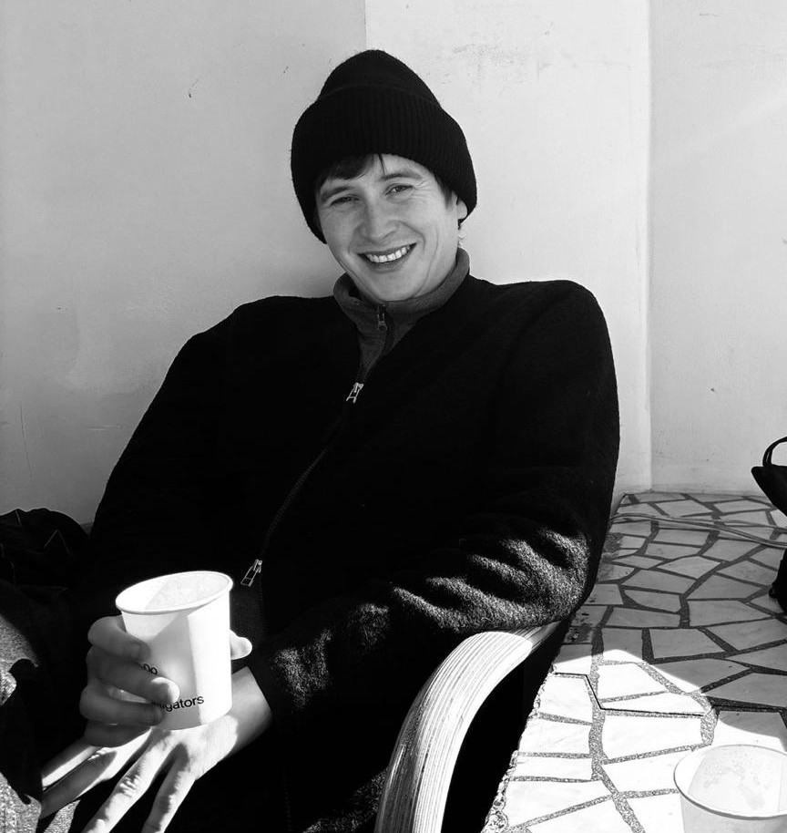 Shaun Barry smiling, seated outside with a coffee